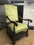 Ein antiker Sessel mit grünem Bezugsstoff